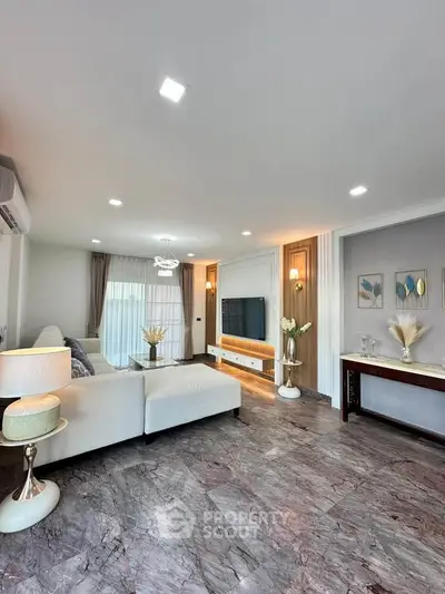 Elegant living room with modern decor and marble flooring, featuring a cozy white sectional sofa and stylish lighting.