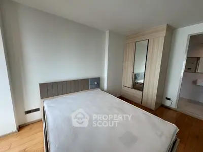Spacious bedroom with modern wardrobe and hardwood flooring in a stylish apartment.