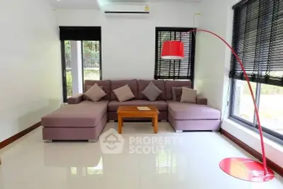 Modern living room with stylish furniture and large windows, featuring a cozy sectional sofa and vibrant floor lamp.
