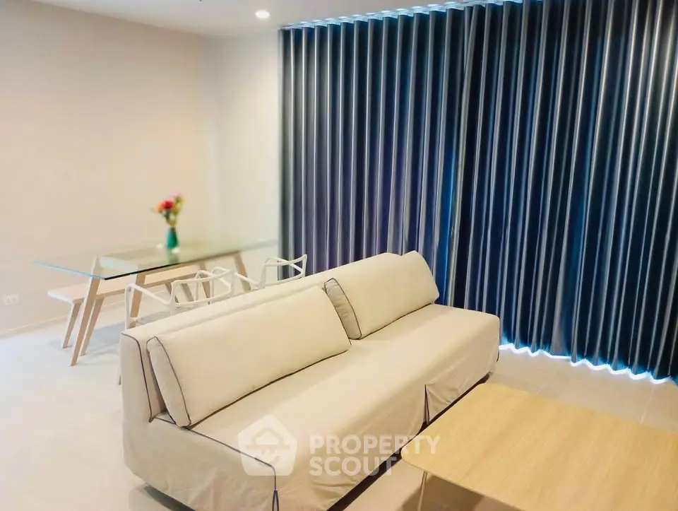 Modern living room with elegant sofa, glass dining table, and stylish curtains in a contemporary apartment.