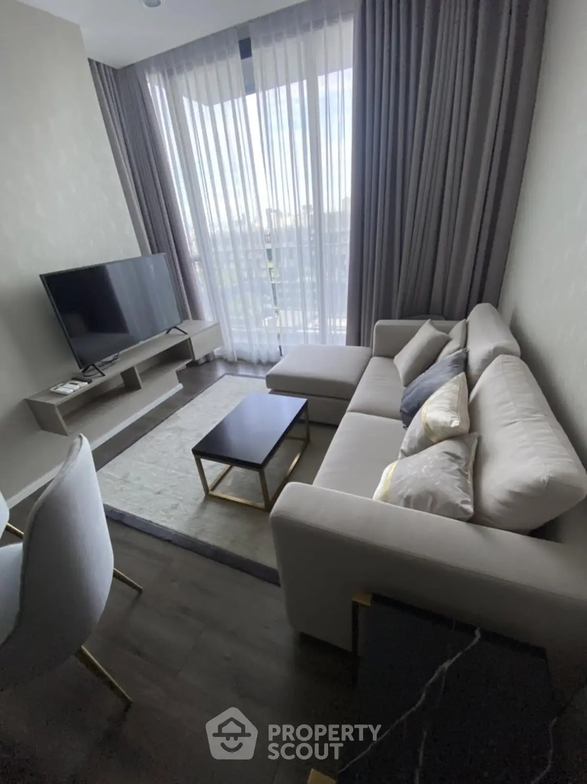 Modern living room with sleek furniture and large window offering natural light.