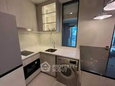 Modern kitchen with sleek appliances and marble countertops in a compact layout.