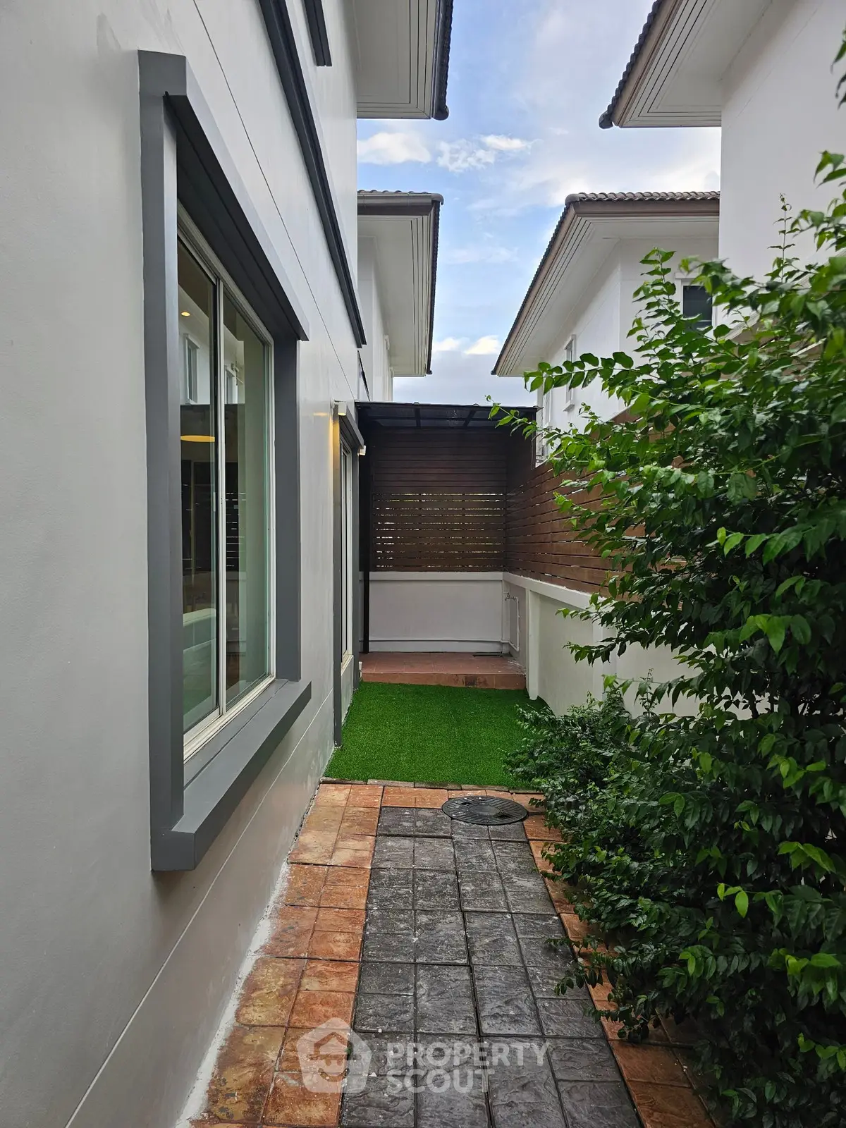 Charming side pathway with lush greenery and modern architecture