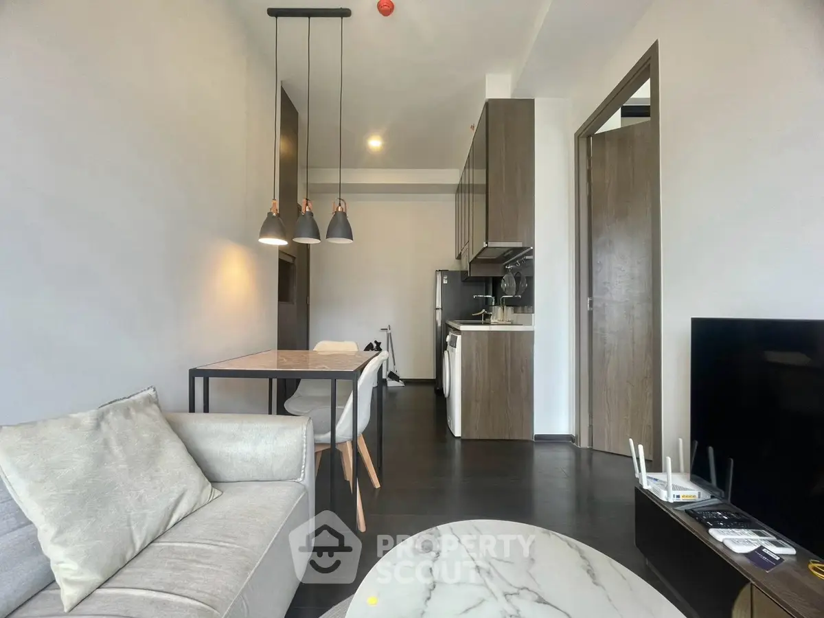 Modern living room with open kitchen, stylish lighting, and elegant marble table.