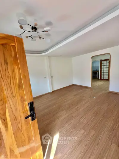 Spacious empty room with wooden flooring and modern lighting, ideal for customization.