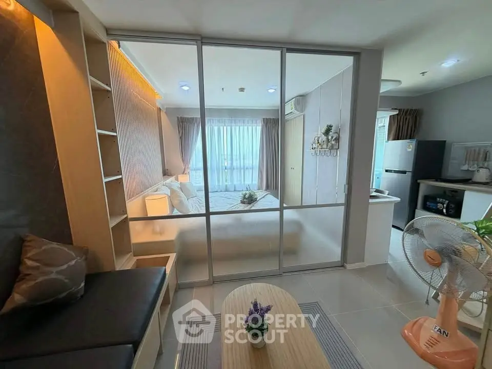 Modern studio apartment with glass partition, cozy living area, and stylish kitchen.