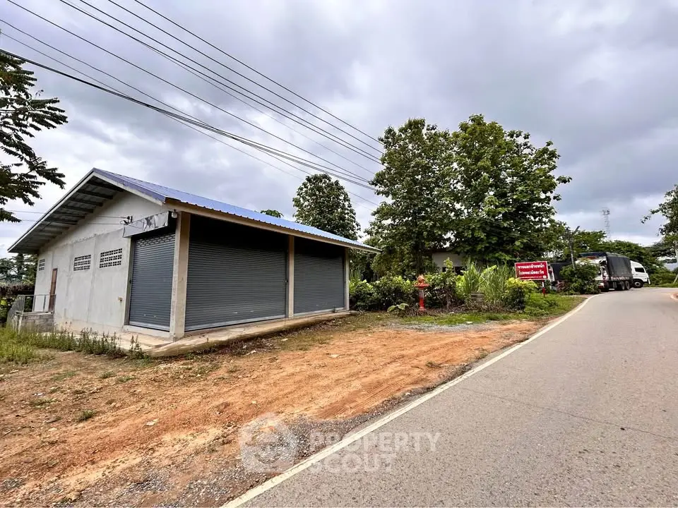 Commercial property with metal shutters on a roadside, ideal for business opportunities.