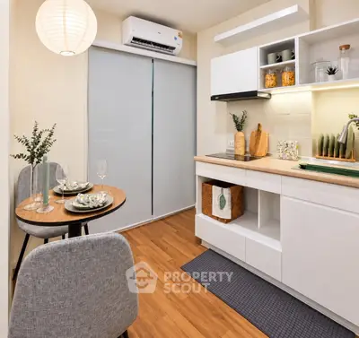Modern kitchen with sleek white cabinets and cozy dining area, perfect for urban living.