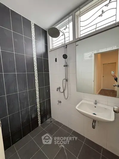 Modern bathroom with sleek black and white tiles and rainfall showerhead.