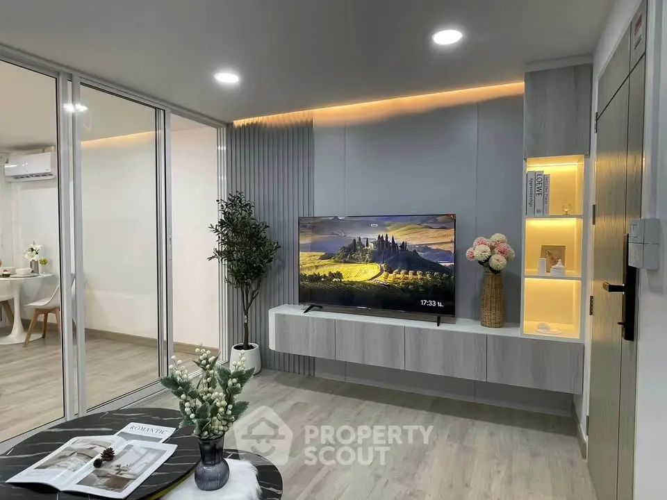 Modern living room with sleek design, featuring a wall-mounted TV, stylish decor, and open layout leading to dining area.