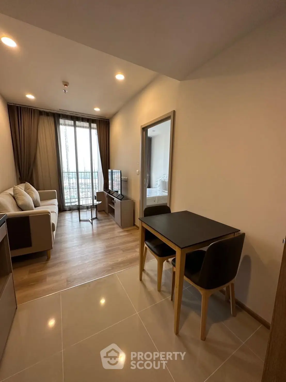 Modern living room with cozy seating and dining area, featuring elegant decor and natural light.