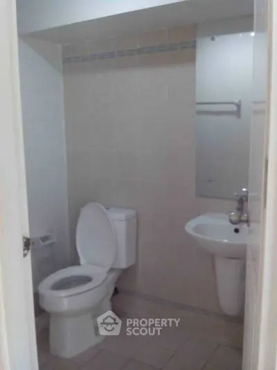 Compact bathroom with toilet, sink, and mirror in a modern apartment.