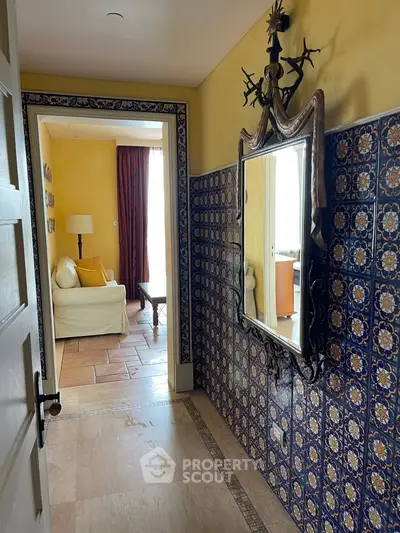 Charming hallway with ornate mirror and tiled walls leading to cozy living room with natural light.