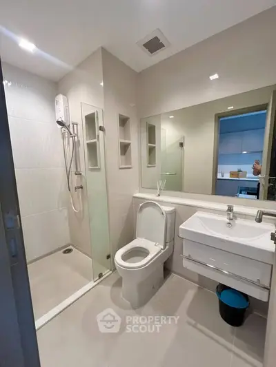 Modern bathroom with glass shower and sleek fixtures in contemporary apartment.
