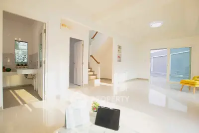 Bright modern living room with open layout and staircase, featuring sleek tile flooring and natural light.
