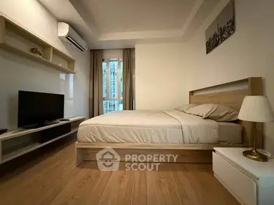 Modern bedroom with wooden flooring, stylish bed, and wall-mounted TV in a cozy apartment.