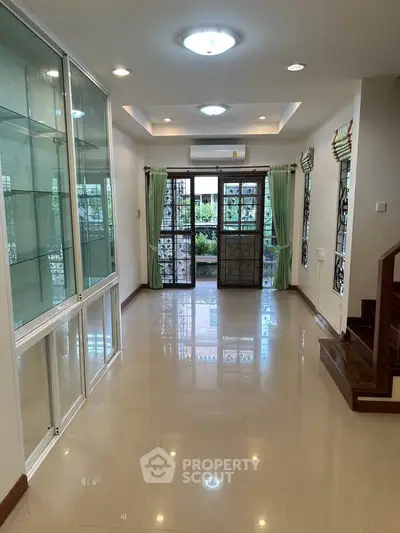 Spacious living room with glass cabinets and garden view, perfect for family gatherings.
