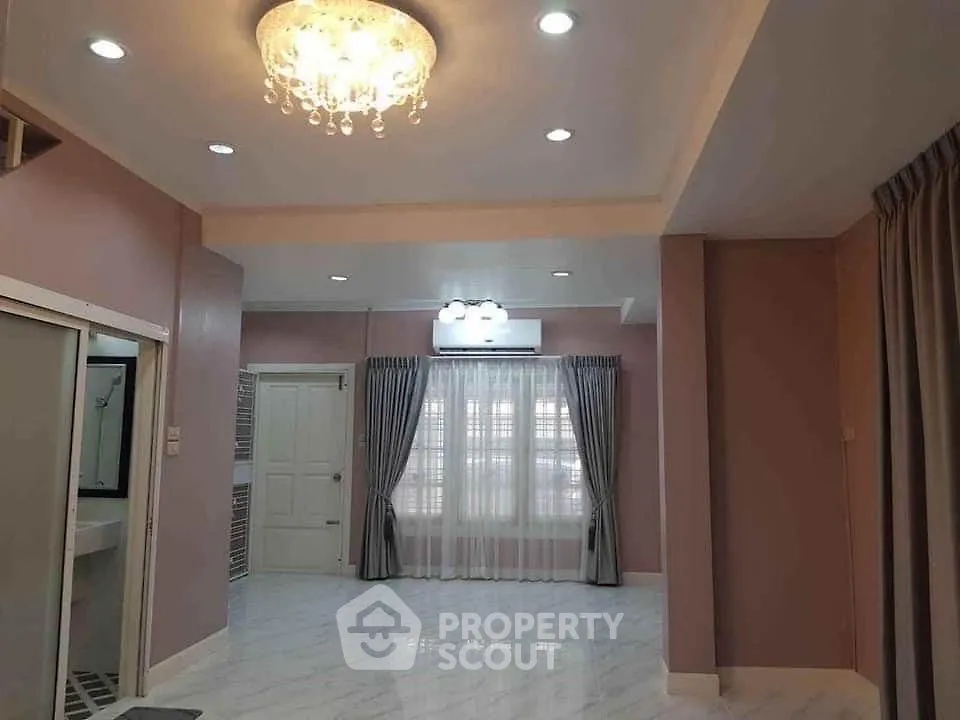 Spacious living room with elegant chandelier and large window drapes