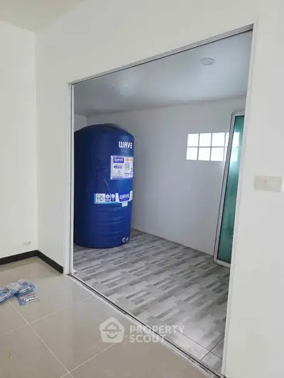 Spacious utility room with water storage tank and tiled flooring in modern home.