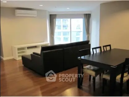 Spacious modern living room with wooden flooring and large window view.