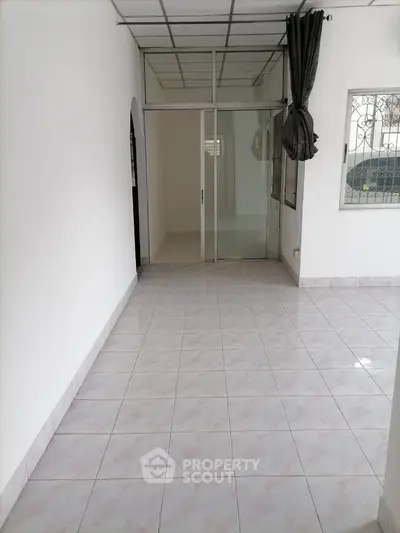 Spacious tiled room with large window and sliding glass door, ideal for versatile living space.