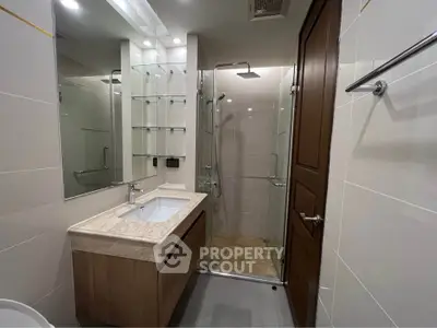 Modern bathroom with glass shower and sleek vanity in a contemporary apartment.