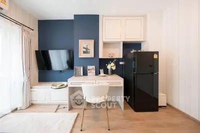 Modern living room with stylish decor, wall-mounted TV, and sleek black fridge in a cozy apartment.
