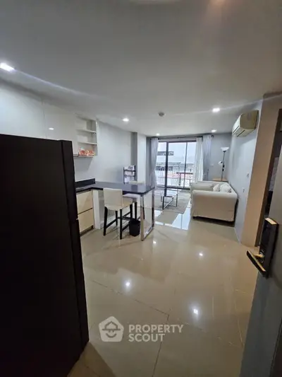 Spacious modern living room with open kitchen and balcony view, perfect for urban living.