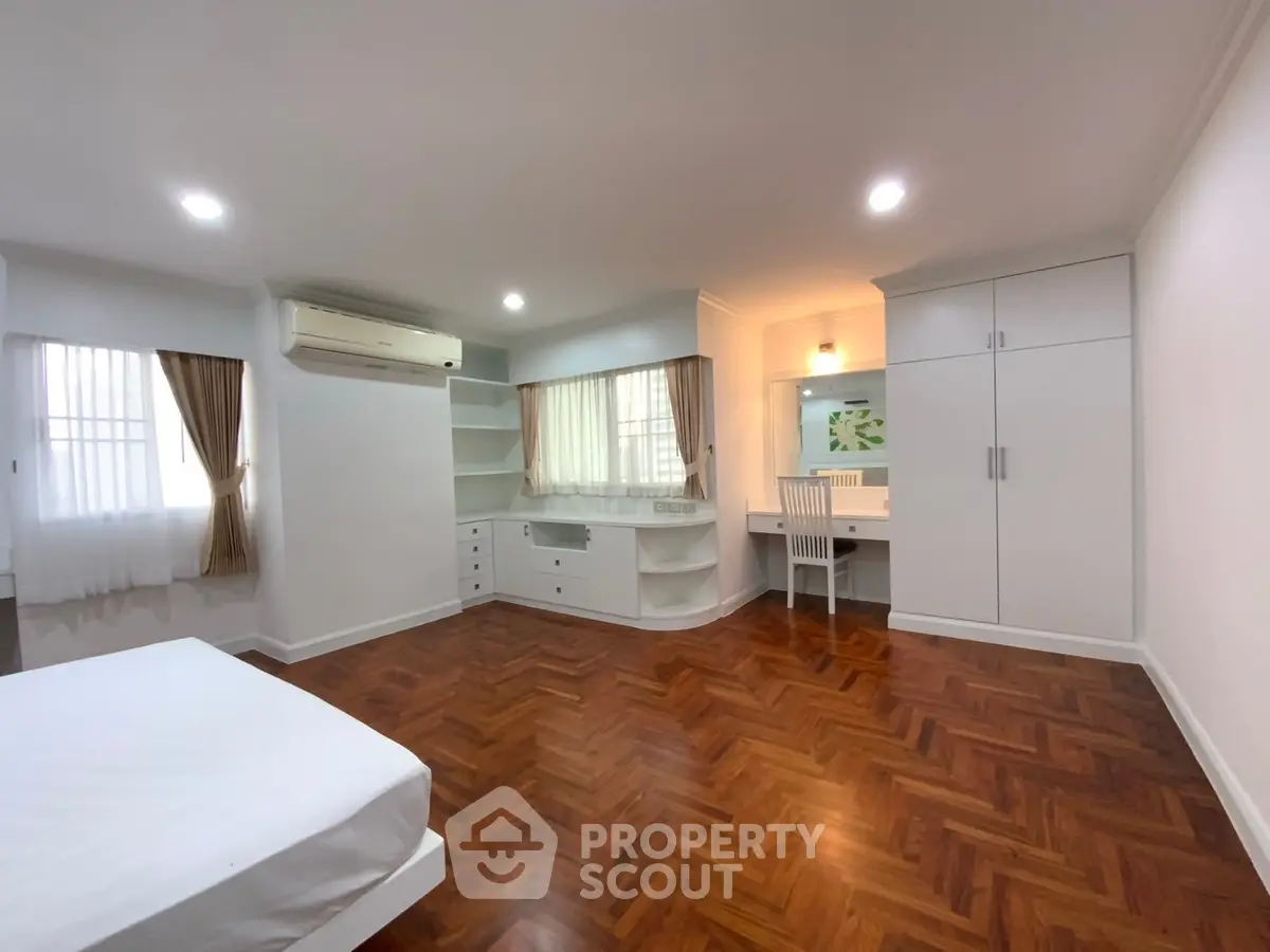 Spacious bedroom with elegant wooden flooring and built-in storage solutions.