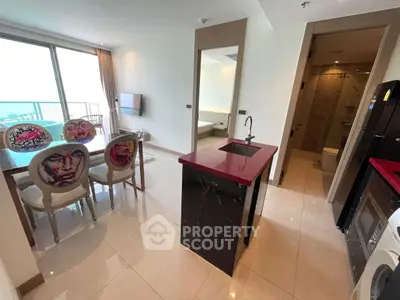 Modern open-plan living area with stylish kitchen and dining space, featuring unique chair designs and ocean view.