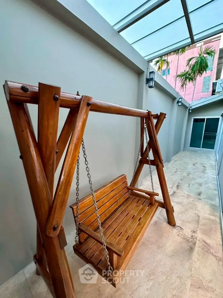 Charming wooden swing in a modern outdoor patio with skylight.