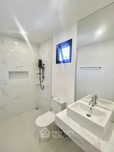 Modern minimalist bathroom with sleek fixtures and marble walls.