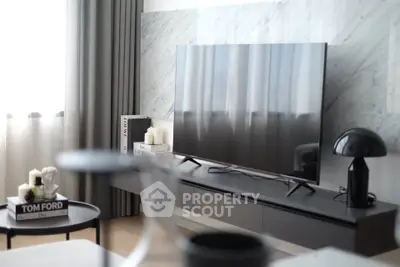 Modern living room with sleek TV, stylish decor, and natural light.