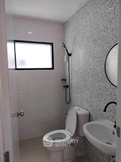 Modern bathroom with sleek design, featuring a round mirror, white tiles, and a compact shower area.