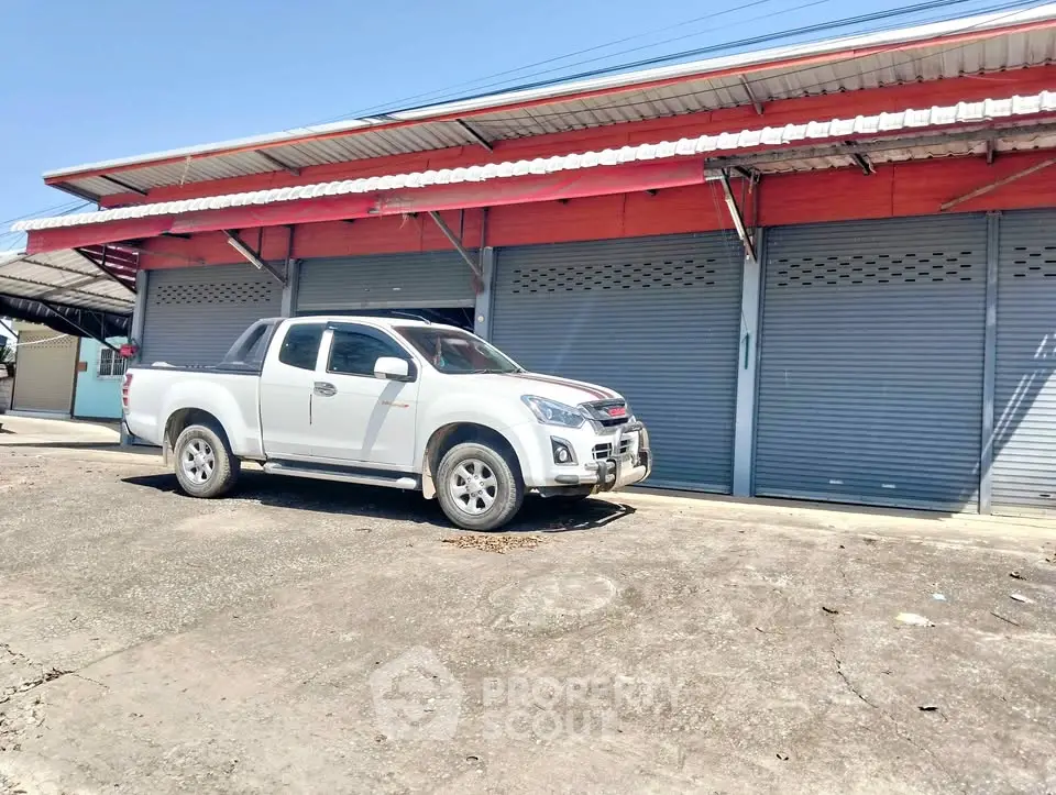 Commercial property with closed shutters and a parked pickup truck in front, ideal for business opportunities.