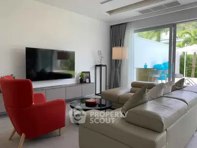 Modern living room with sleek furniture and large TV, opening to a bright patio area.
