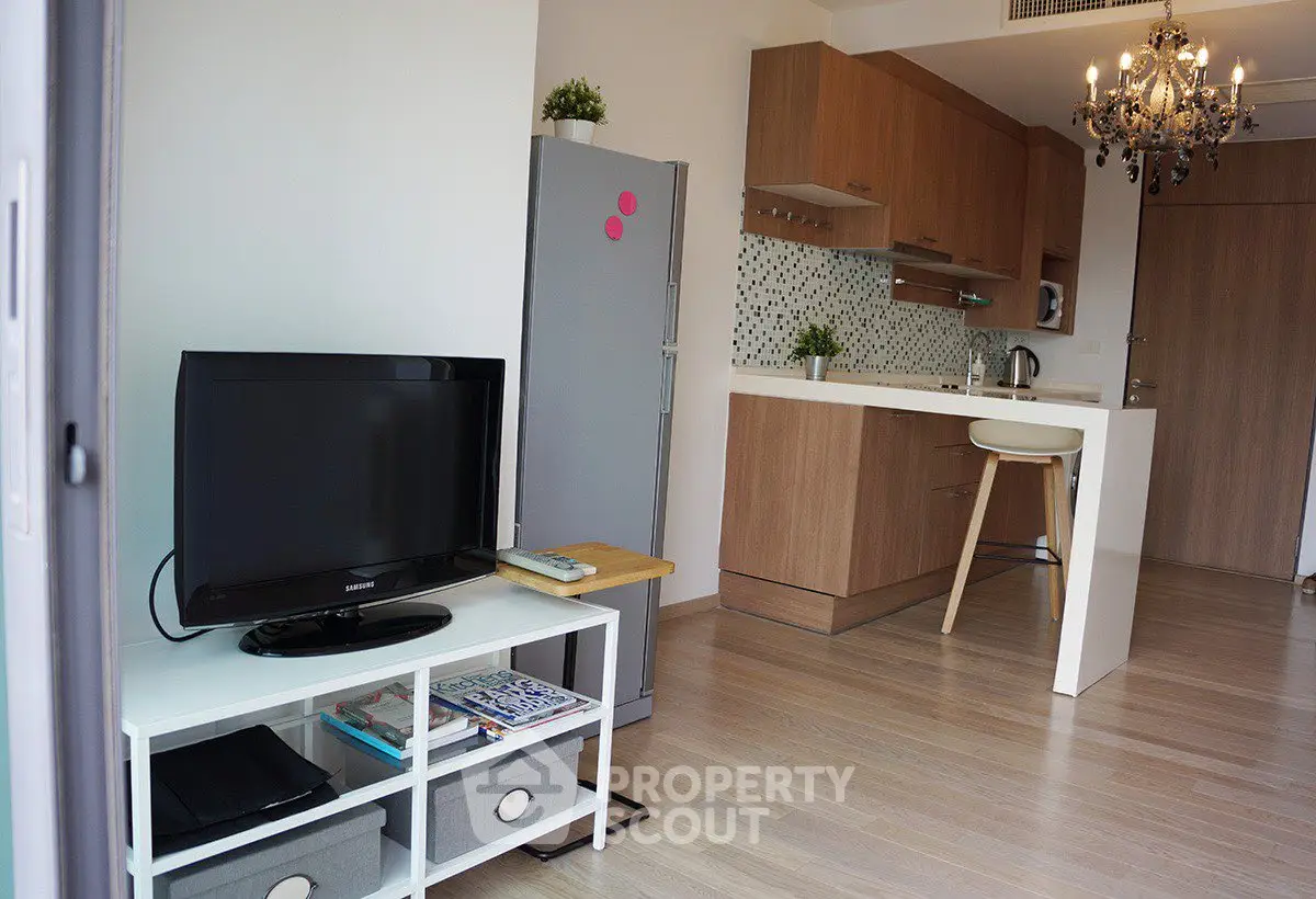 Modern open-layout kitchen and living room with stylish chandelier and sleek appliances.