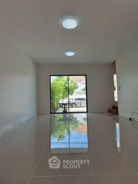 Spacious empty living room with glossy tiled floor and large window view.