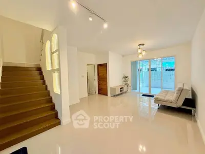 Spacious modern living room with sleek staircase and large windows for natural light.