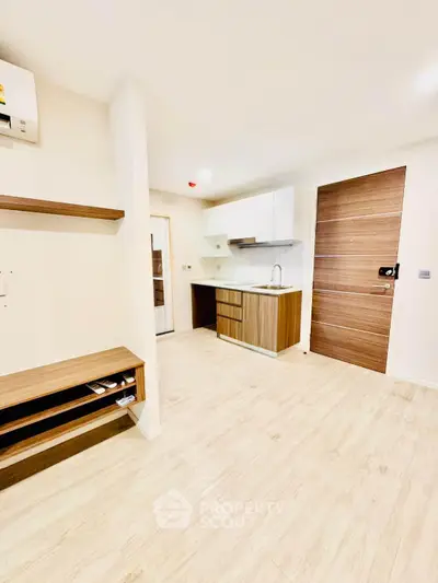 Modern minimalist kitchen with wooden cabinetry and open layout in a bright apartment.