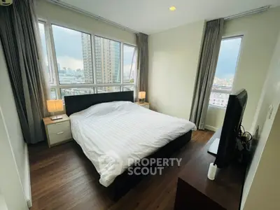 Spacious bedroom with city view, featuring large windows and modern furnishings in a high-rise apartment.
