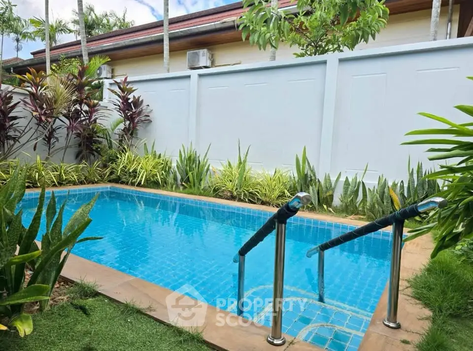 Charming backyard with a private pool surrounded by lush greenery and privacy fence.