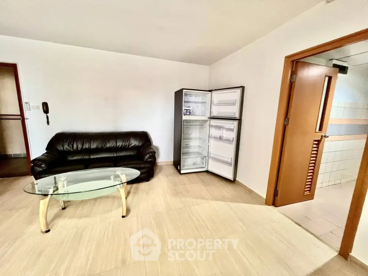 Spacious living room with leather sofa and open fridge, modern glass coffee table.