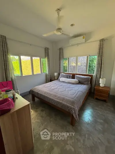 Cozy bedroom with large windows and modern decor, perfect for relaxation.