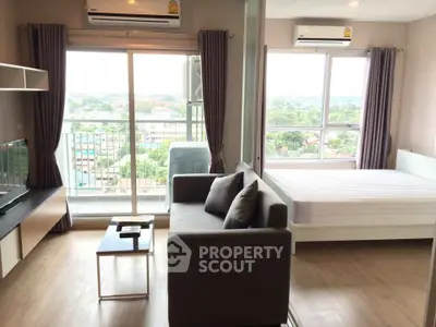 Modern studio apartment with balcony and scenic view, featuring cozy living area and bedroom.