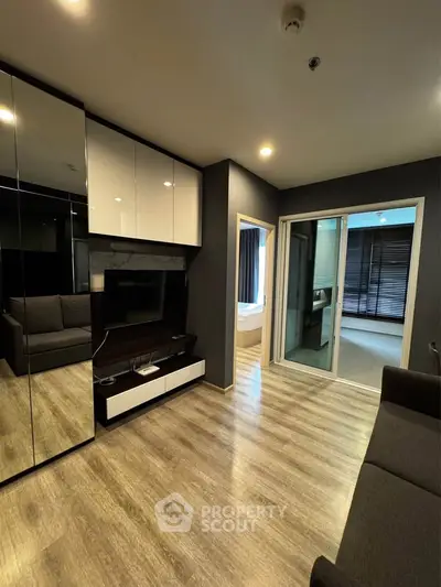 Modern living room with sleek design, featuring a mirrored wall, cozy sofa, and sliding glass doors leading to a balcony.