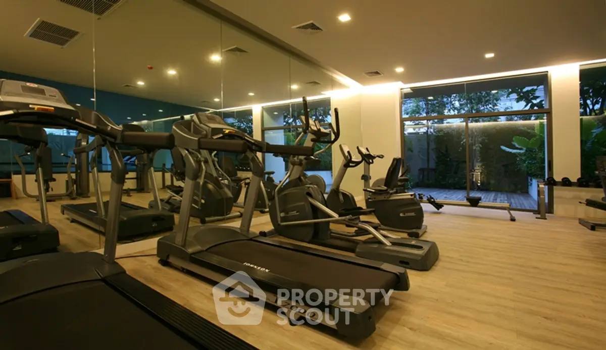 Modern gym with state-of-the-art equipment and large mirrors in luxury real estate property.