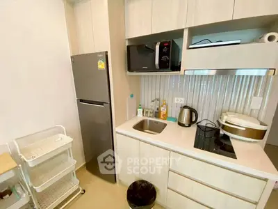 Modern kitchen with sleek appliances and compact design, featuring a fridge, microwave, and induction cooktop.