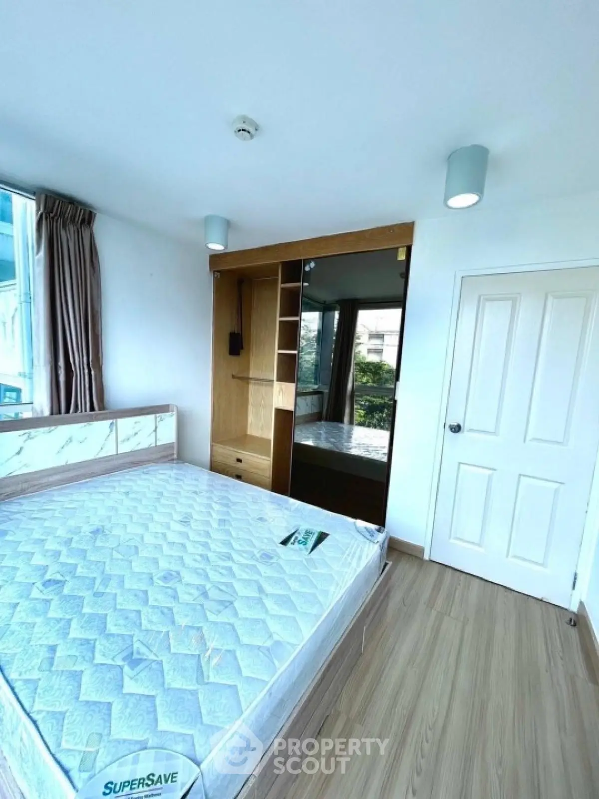Bright bedroom with large window and built-in wardrobe, featuring a comfortable bed and modern lighting.