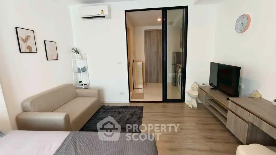 Modern living room with cozy sofa, TV unit, and washing machine in a sleek apartment.